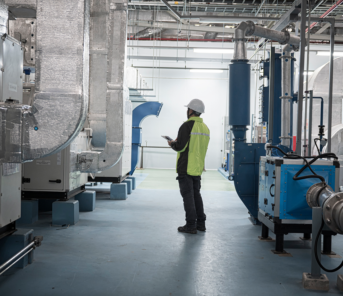 Worker inspecting industrial machinery in factory.