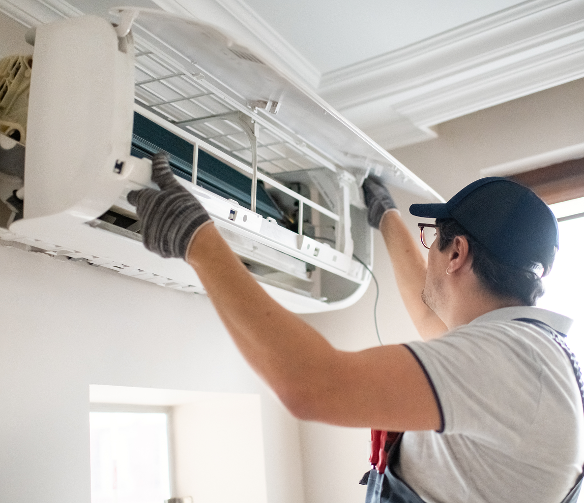 Technician servicing a wall-mounted air conditioner.